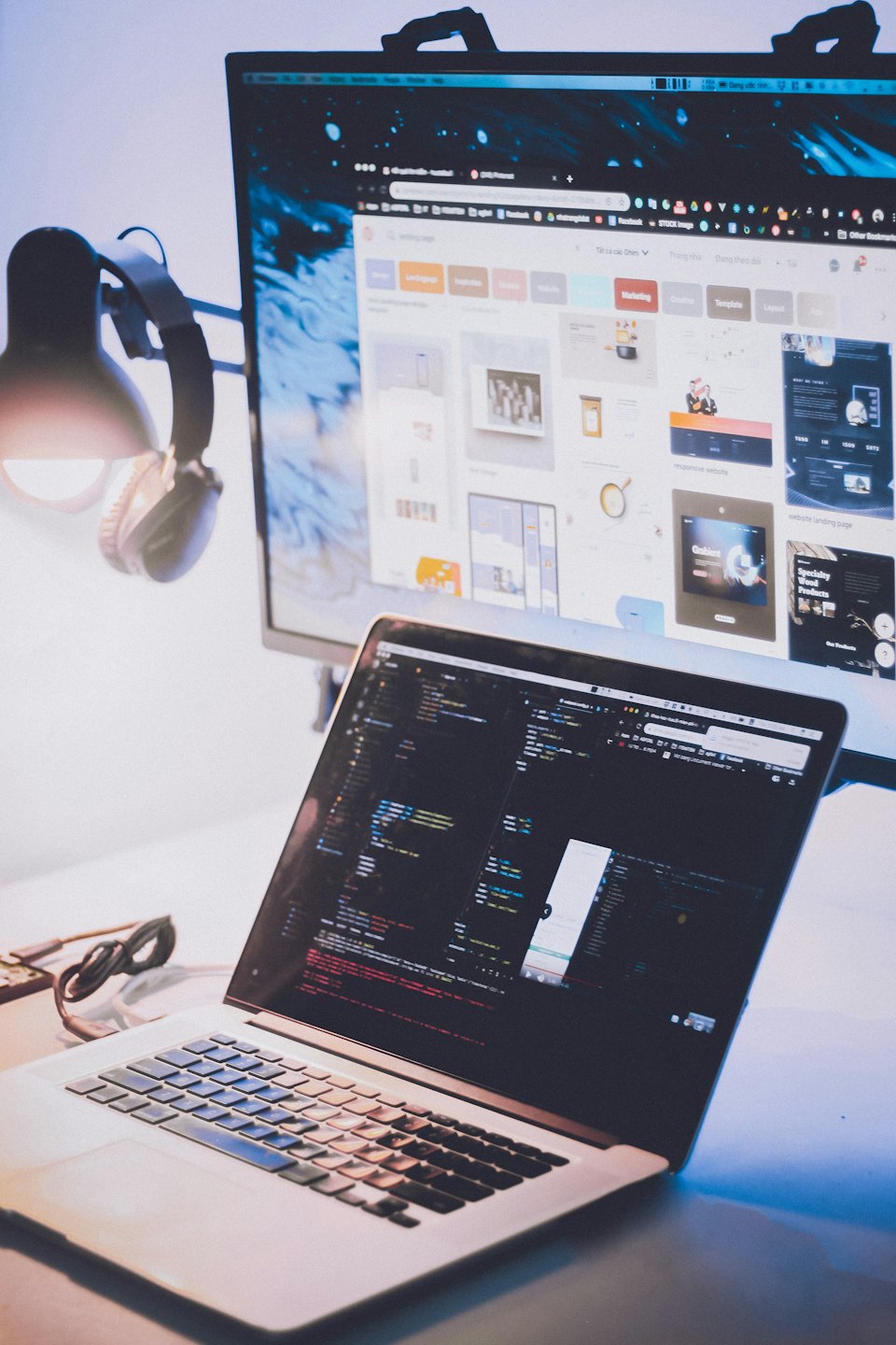 Biurko programisty z laptopem wyświetlającym kod i zewnętrznym monitorem w nocy.